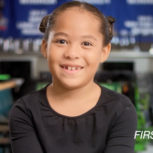 Eva, a school child, sitting in a classroom, smiling at the camera.