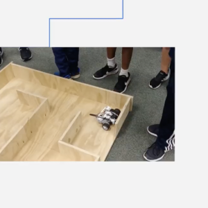students standing around a wooden maze for a robotic vehicle
