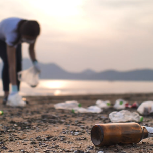 Two people picking up trash on a beach.