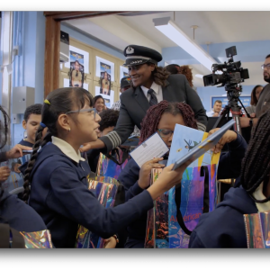 American Airlines pilot speaking with a group of children holding the Bessie Coleman doll 