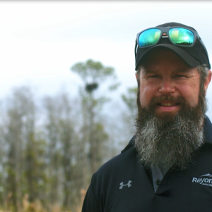 A Rayonier employee looks at the camera, an eagle's nest far in the distance.