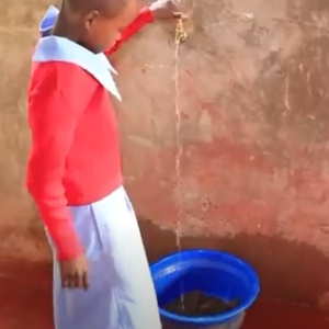 Young girl turning water on from a spigot