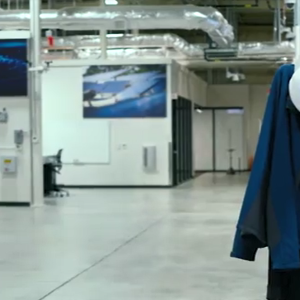 An empty industrial room, coat and hardhat on a stand.