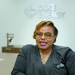 LaQuitta Gent, seated in a conference room. "Duke Energy" sign behind her.