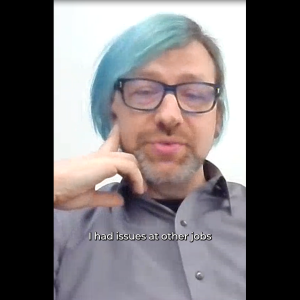A person in glasses and a streak of light blue hair in a virtual meeting. "I had issues at other jobs."
