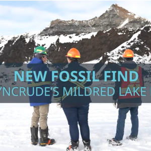 People standing in front of mountain with text "New Fossil Find at Syncrude's Mildred Lake Mine"