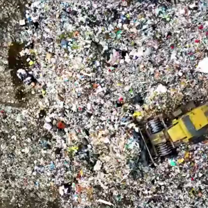 A bulldozer pushing piles of garbage in a dump.
