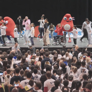 Adults and kids dancing on a stage in front of a crowd.
