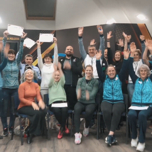 A group of people seated and standing with arms raised.