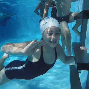 A child swimming under water smiling.
