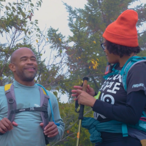 two hikers talking in front of trees