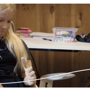 Sasha smiling and using her prosthetic arm