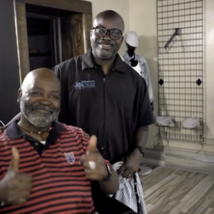 Teto Wilson and a client giving the thumbs up in his barbershop.