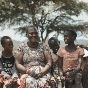 Lucy Tomee and four children sitting on a bench outside.