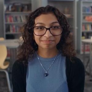 Person wearing glasses and a blue top , smiling into the camera
