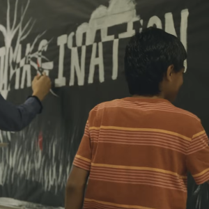 A child writing on a black board 