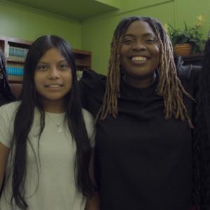 Four people with arms around each other, smiling.