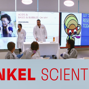 Two scientists in lab coats in front of a room of seated children. "Henkel Scientists" at the bottom.