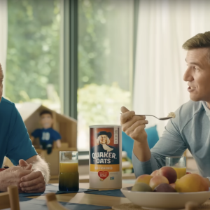 Two people sat at a dining table, one person eating a bowl of quaker oats