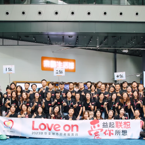 Large group posed, holding a large banner "Love On" and other writing in a foreign language.