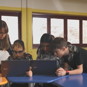 Students and a teacher in a classroom using laptop computers.