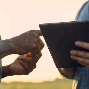 Two people close together outside. One using a tablet device.