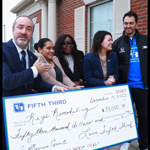 Staff and volunteers hold a large check outside.