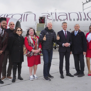 A group of people pose in front of a Virgin Atlantic plane.