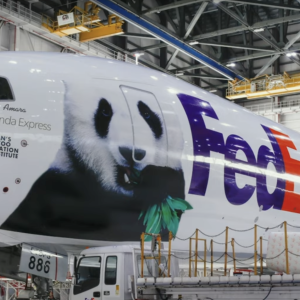 Photo of a large plane in an airplane hangar with the FedEx logo and an image of a giant panda on the side along with the words, "FedEx Panda Express"