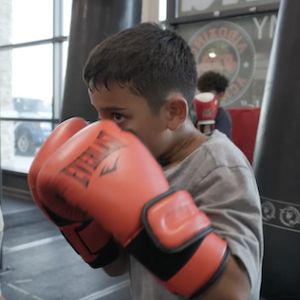 Young boy shown in the A1 Boxing club. He is wearing gloves and is ready to box.
