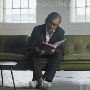 A person sat on a green sofa reading a book