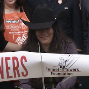 U.S. Army Specialist (SPC) Maggie Bilyeu shown cutting the ribbon in front of her new home.