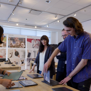 People stood around a desk which has laptops on