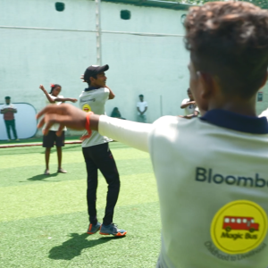 People stretching in a grass courtyard, wearing matching shirts "Bloomberg Magic Bus" 