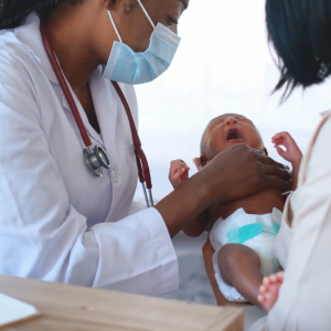 A medical provider and another adult holding an infant in a diaper.