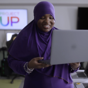 person smiling and holding up a laptop