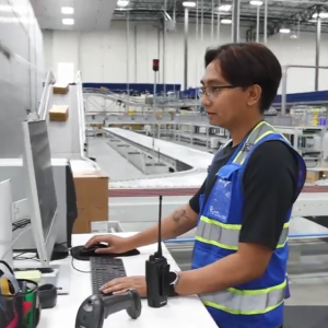 Jerenez Rivera standing at a computer station next to conveyor lines.