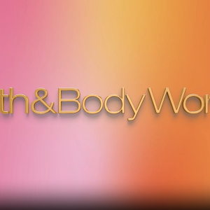 Lively music introduces two Black women speaking about their creative process, self expression and candle collection for Bath & Body Works. Candles sit on display and cameras snap photos of the women smiling together in a studio.