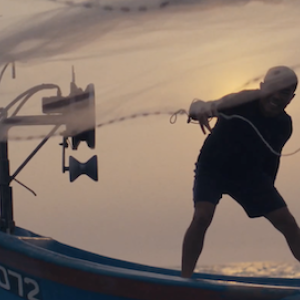 A fisherman casting a net from a fishing boat.