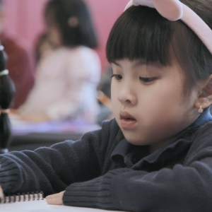 Children sketching in a room of others.