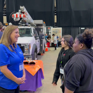 An adult talking to two young people at an event