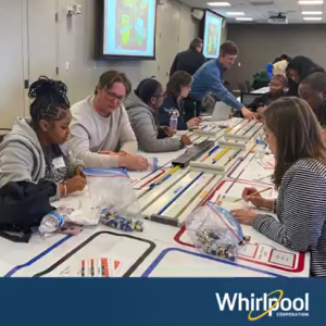 Students and mentors working on a project on a long strip of paper with colored areas.
