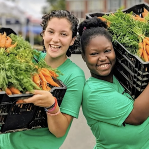 2 people holding baskets of carrots