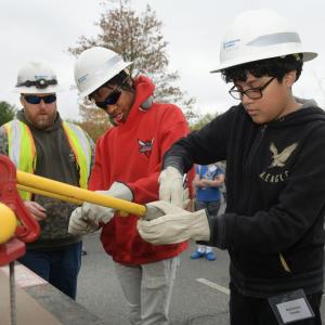 students in hard hats working on equipment outside
