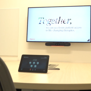 A screen on the wall that reads "Together, we can accelerate patient access to life-changing therapies"