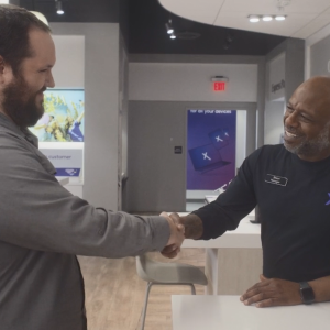 An employee and customer smiling and shaking hands.