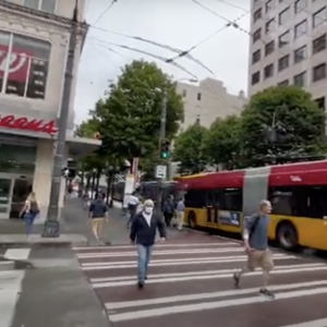 pedestrians crossing a city street in front of a Walgreens
