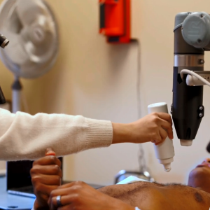 A person laying down receiving an ultrasound, a medical professional applying gel to their chest.