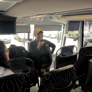 Kascia standing at the front of a charter bus