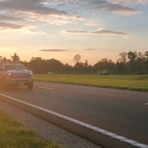 Truck on the highway with a sunset behind it
